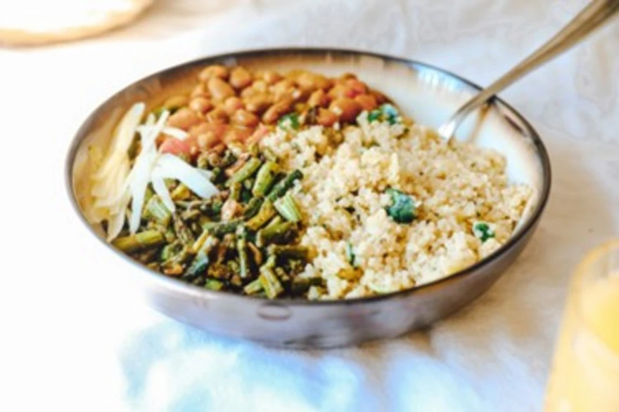 Bowl of cooked quinoa with vegetables and herbs