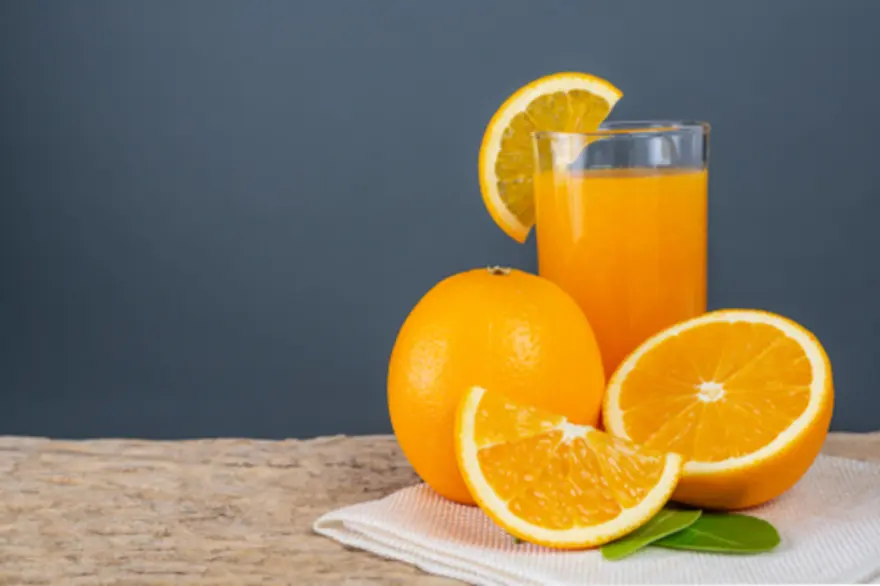 Glass of orange juice on table with fresh oranges